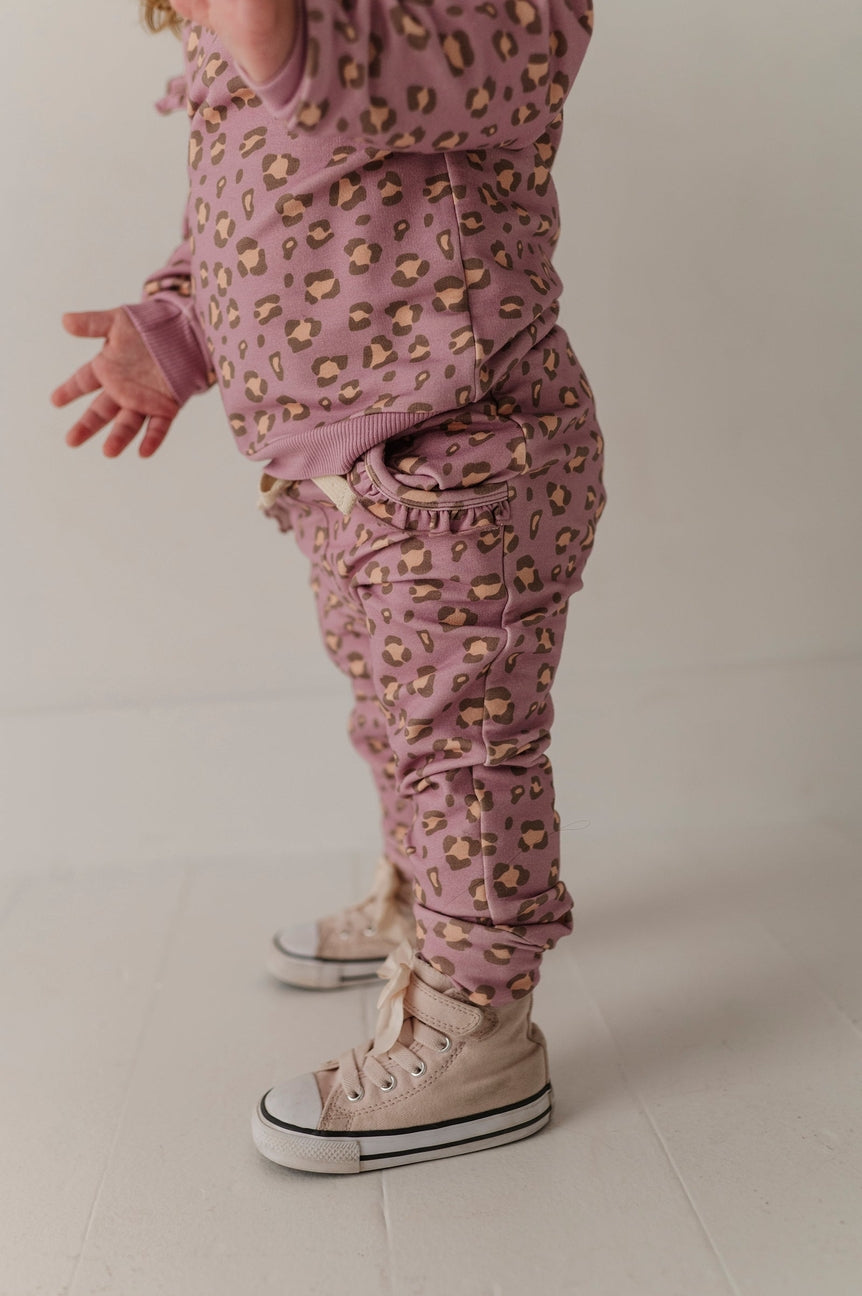 Person wearing a pink leopard print outfit with white sneakers on a plain background
