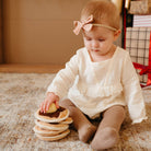 Child playing with a stack of wooden toys on a carpeted floor.