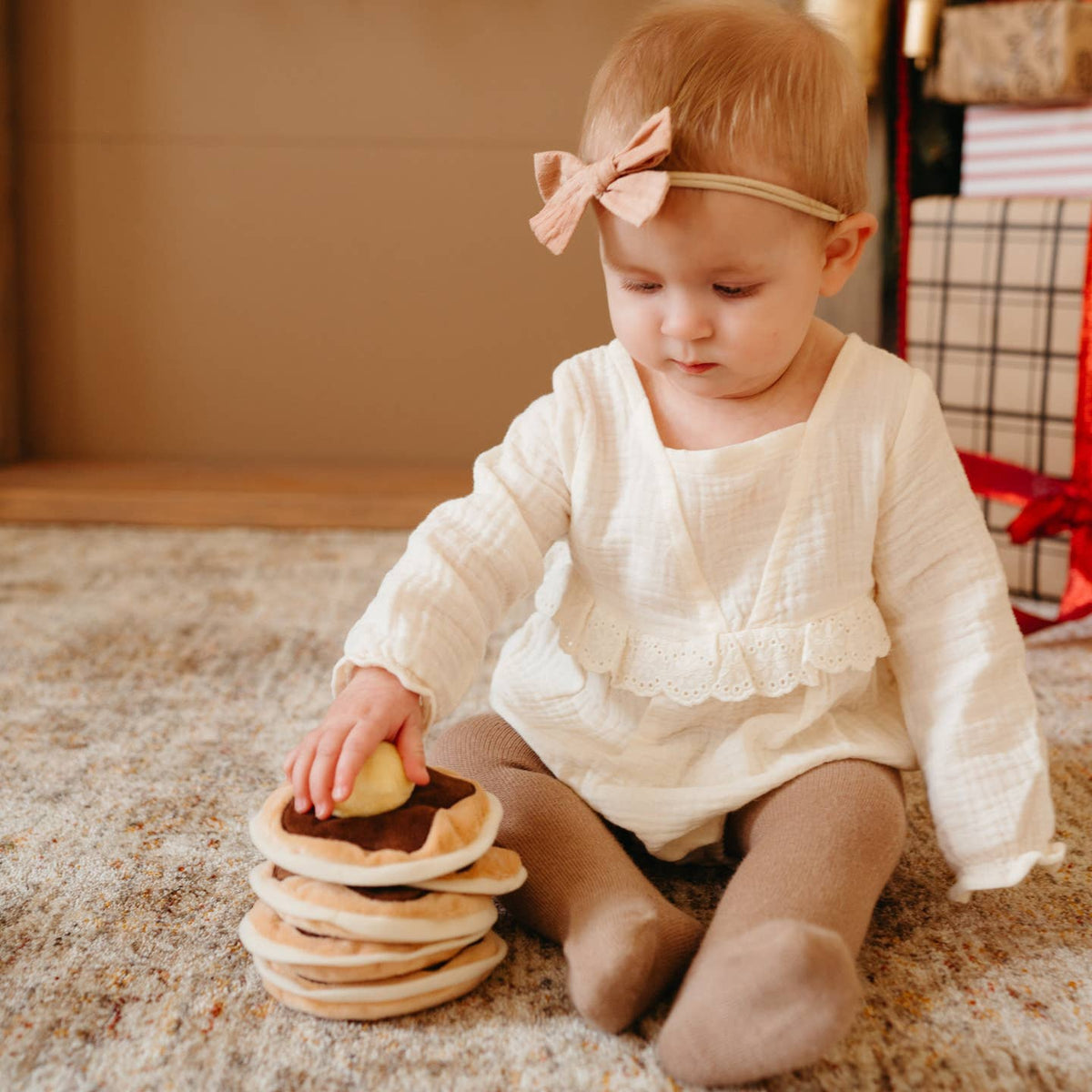 Child playing with a stack of wooden toys on a carpeted floor.
