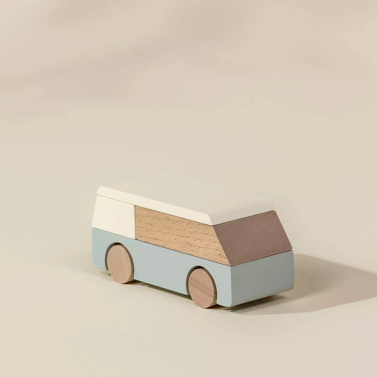 Wooden toy bus with a beige roof, brown side panel, and light blue body on a beige background