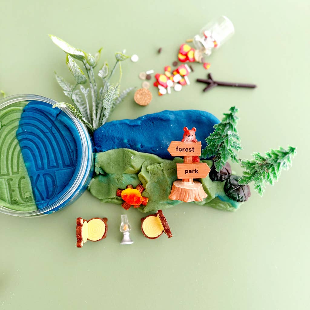 Playdough landscape with a forest park sign, trees, and small figurines on a light green background