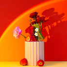 Vase with flowers and strawberries on a red and orange gradient background