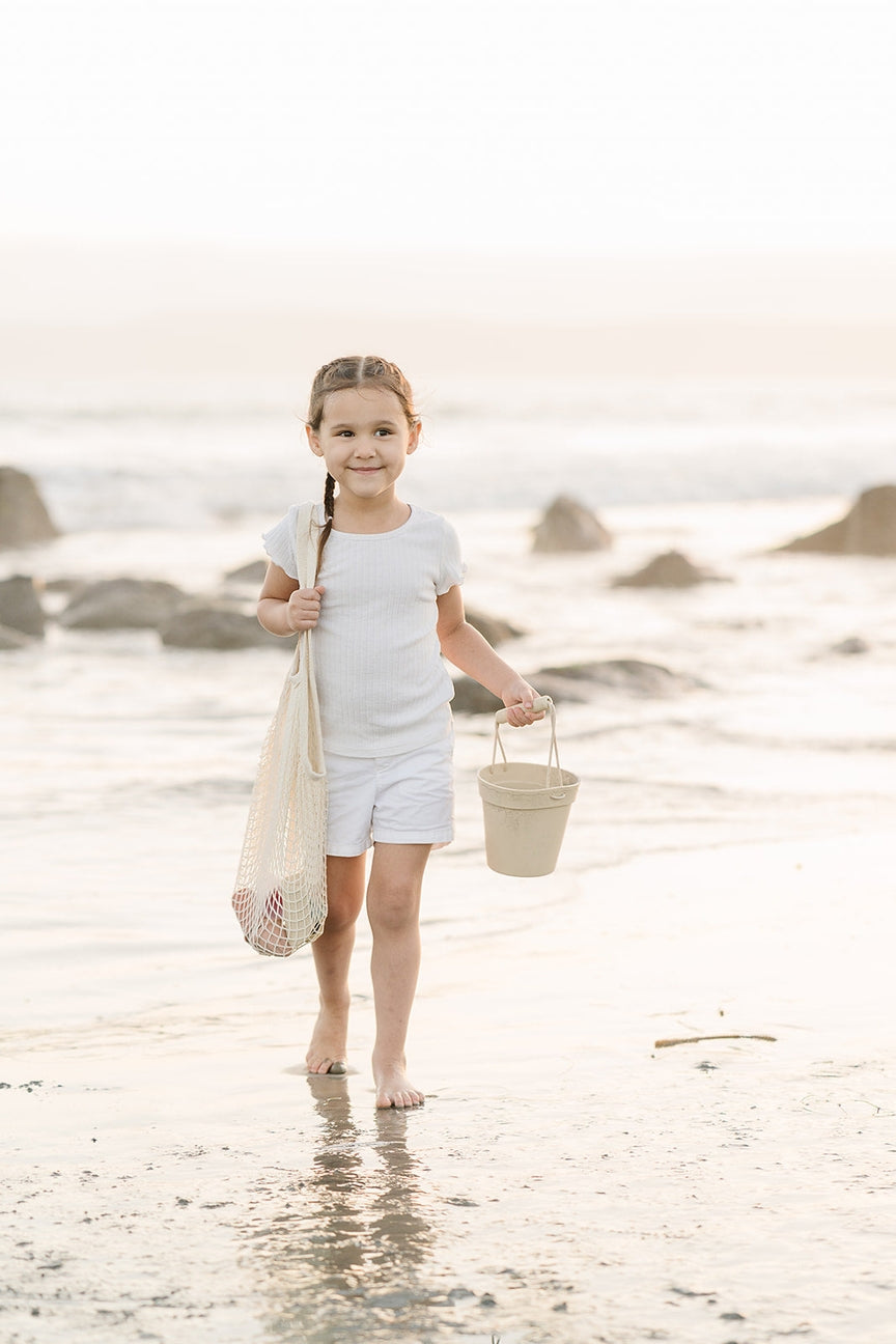 Young girl playing with sand toys holdinga net on a beach