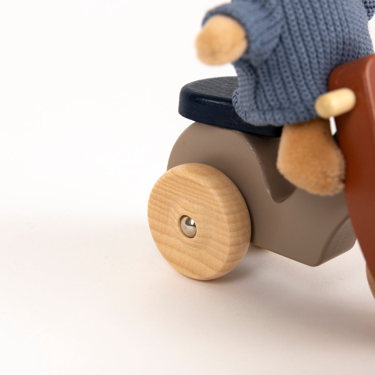 Wooden toy scooter with a plush toy rider on a white background