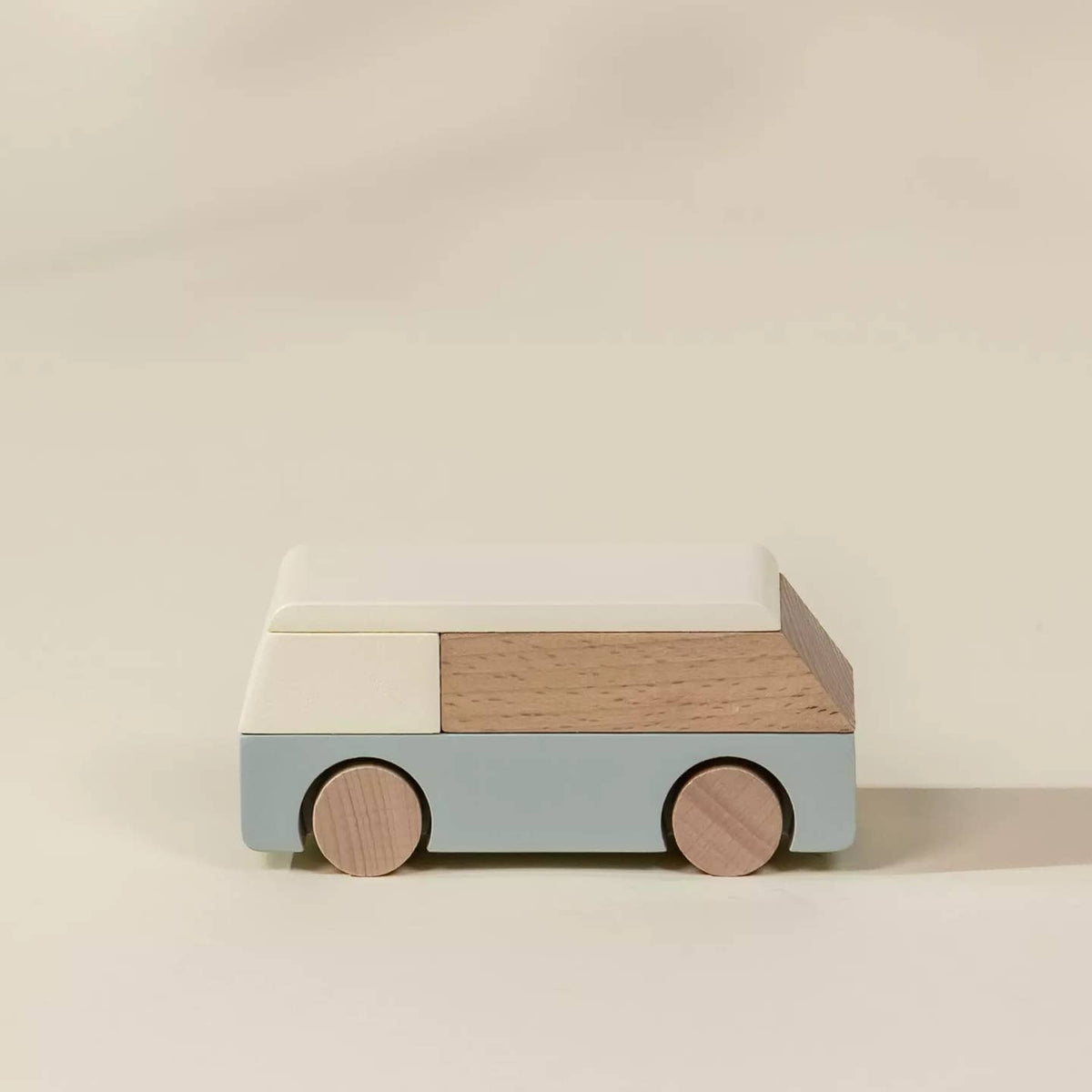 Wooden toy car with a light blue body, beige roof, and brown wheels on a beige background