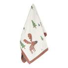 An off-white cotton tea towel with a woodland print featuring a brown moose and green pine trees, finished with a rust-brown ribbed border.