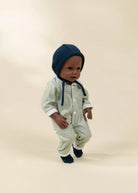 Baby doll wearing a striped outfit and blue bonnet on a beige background