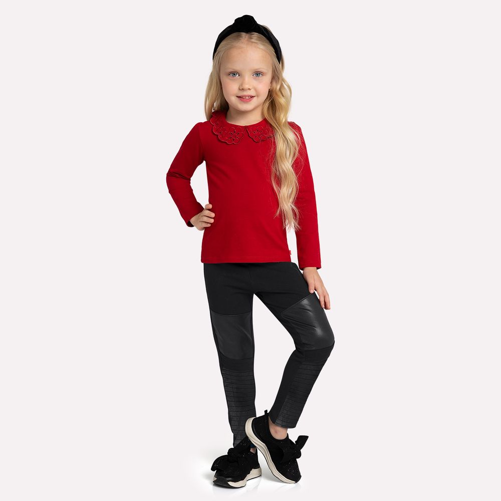 Young girl wearing a red sweater and black pants on a white background