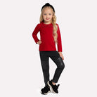 Young girl wearing a red sweater and black pants on a white background