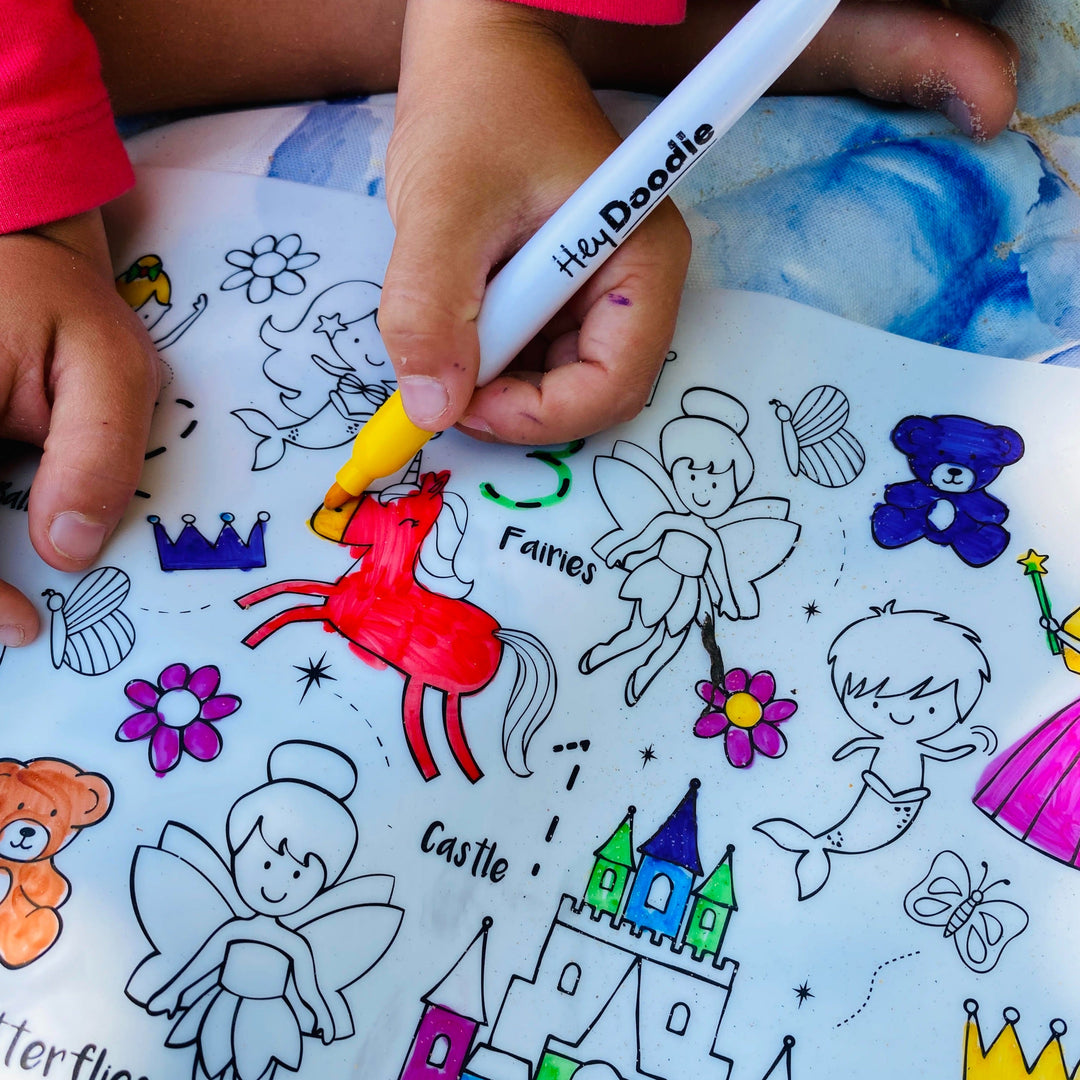 Child coloring a fairy-themed coloring book with a 'HeidiDoodle' marker.