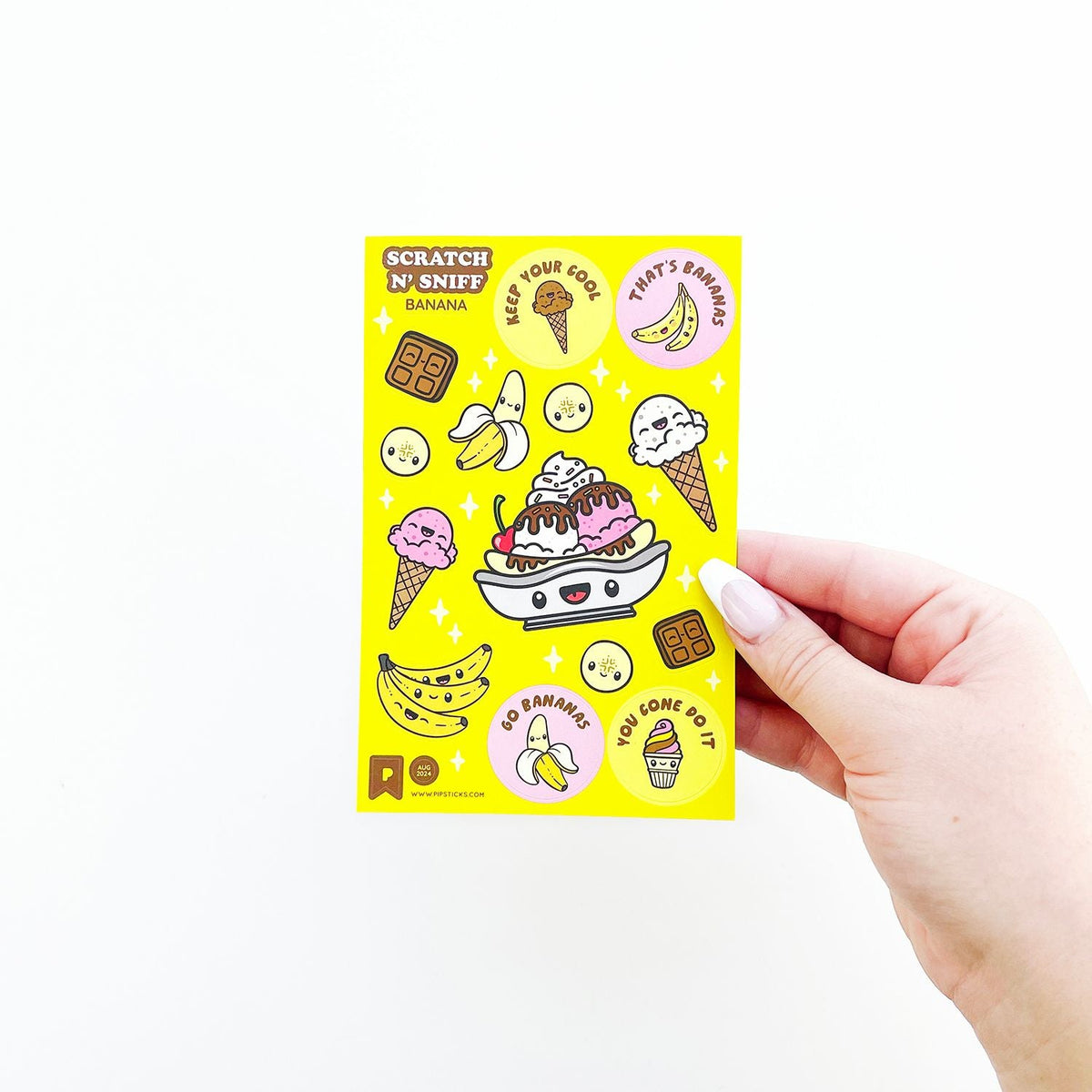 Hand holding a yellow scratch and sniff sticker sheet with ice cream and banana designs.