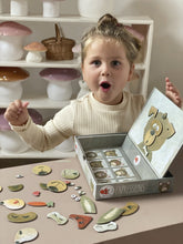 Child with a toy puzzle box on a table with various items in the background