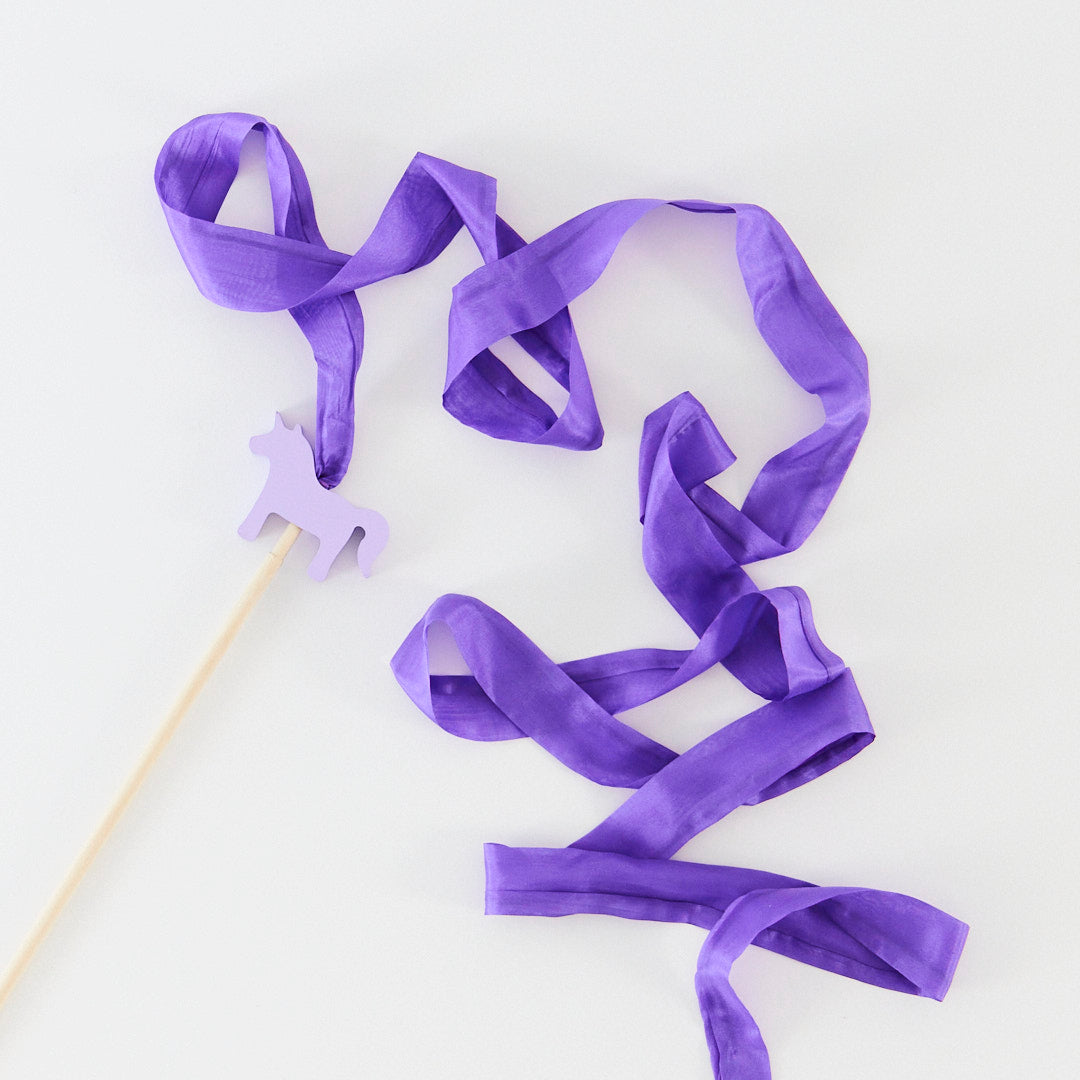 Purple ribbon on a stick with a small purple horse figure on a white background