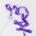 Purple ribbon on a stick with a small purple horse figure on a white background
