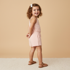 Young girl in a pink outfit standing against a beige background