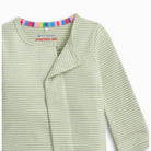 Close-up of a baby long-sleeve top with light green and white horizontal stripes, featuring a wrap-style front and a colorful striped inner collar.