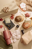 Tabletop scene with beauty products including a scrunchie, pink water bottle, and skincare items.