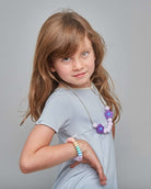 Young girl in a gray dress with jewelry on a gray background