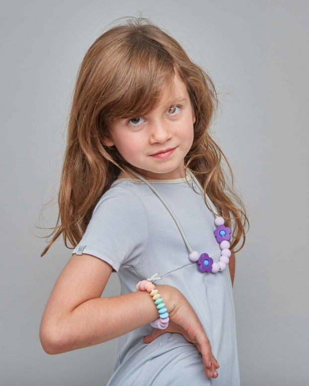 Young girl in a gray dress with jewelry on a gray background