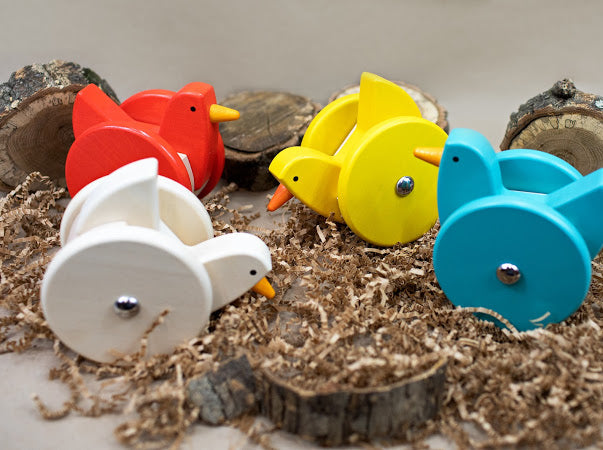 Colorful wooden bird toys with wheels on a natural background