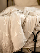 Sheer white curtain with embroidered goose patterns on a window.