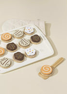 Decorative cookies on a baking tray with a wooden spatula on a beige background