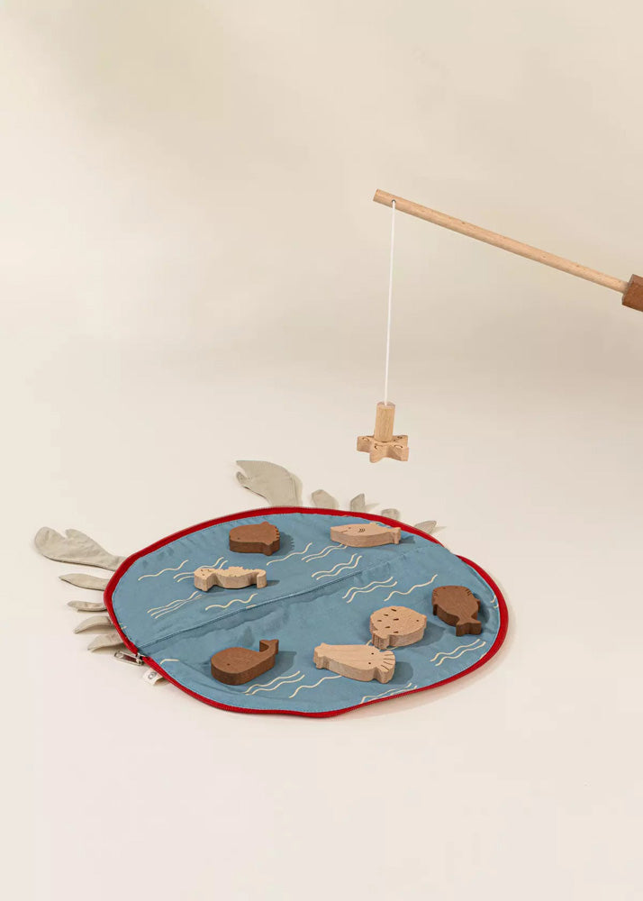 Wooden fishing game with a blue mat, wooden fish, and fishing rod on a beige background