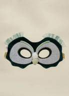 An owl-themed costume mask featuring a dark green plush body, white pinstriped eye panels, a glittery gold beak, and light green ruffled feathers on the sides, shown against a plain beige background.