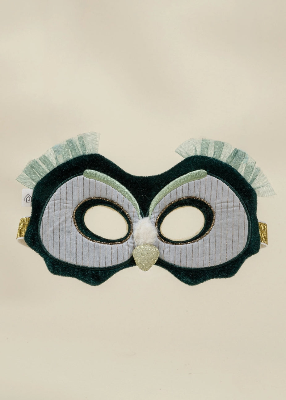 An owl-themed costume mask featuring a dark green plush body, white pinstriped eye panels, a glittery gold beak, and light green ruffled feathers on the sides, shown against a plain beige background.