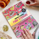 Food-themed draw-along stickers book on a table with snacks.