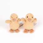 Two small plush duck toys in a warm beige and tan color, standing side by side on a plain white background.