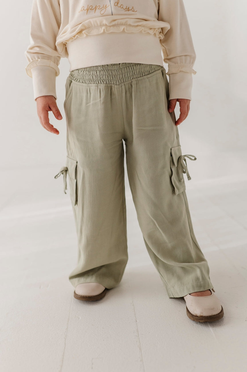 Person wearing beige pants with multiple pockets on a white background