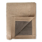 Folded beige blanket with textured corner on a white background