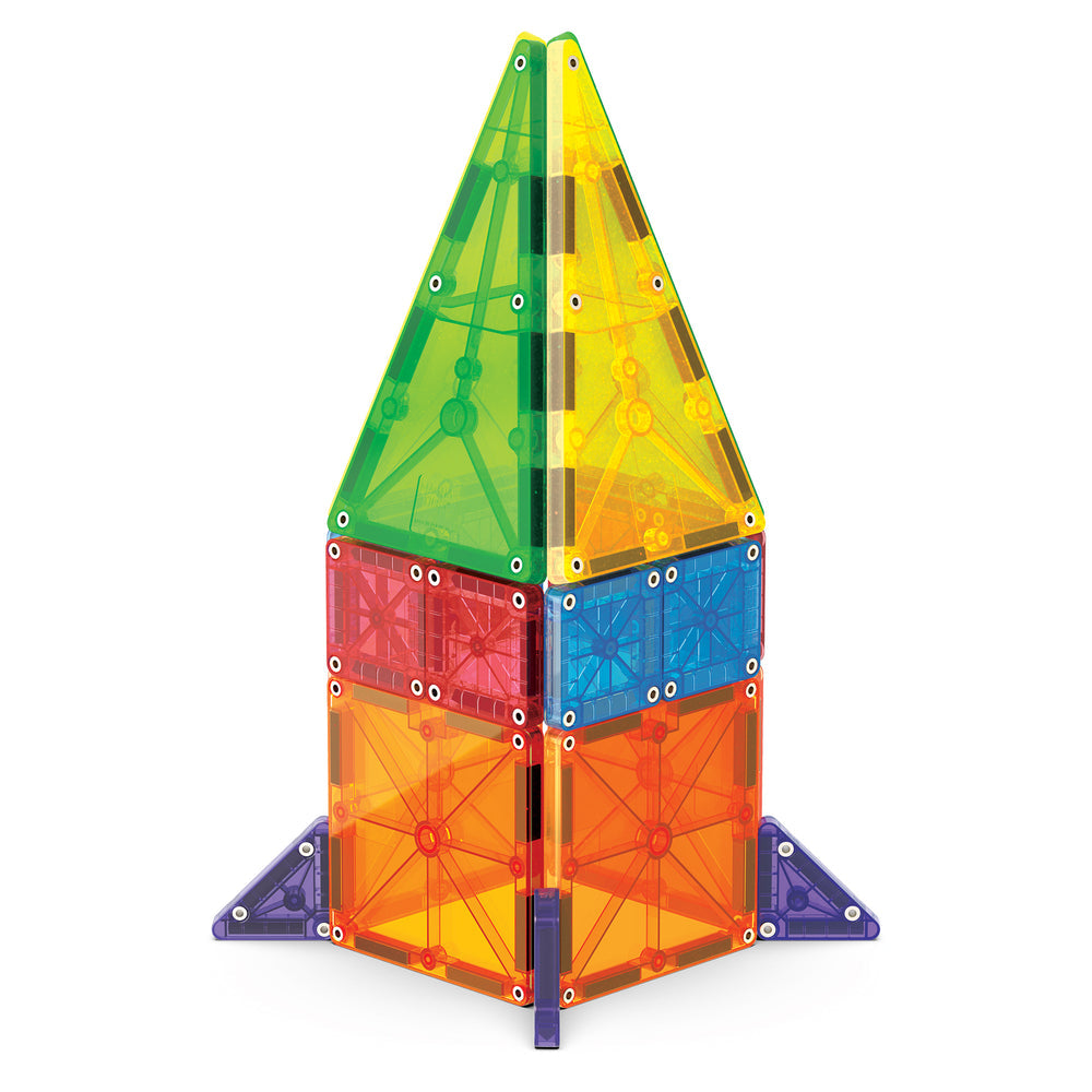 A tall rocket ship structure built with colorful, translucent magnetic tiles from the microMAGS 20 Piece Combo Set by Magna-Tiles, featuring a pointy top, stabilizing fins at the base, and alternating panels of green, orange, purple, and blue.