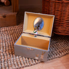 A decorative open jewelry box with a light gray exterior, gold-toned interior, and a small mirror on the inside lid. A tiny mouse figurine stands on a silver stand in front of the mirror.