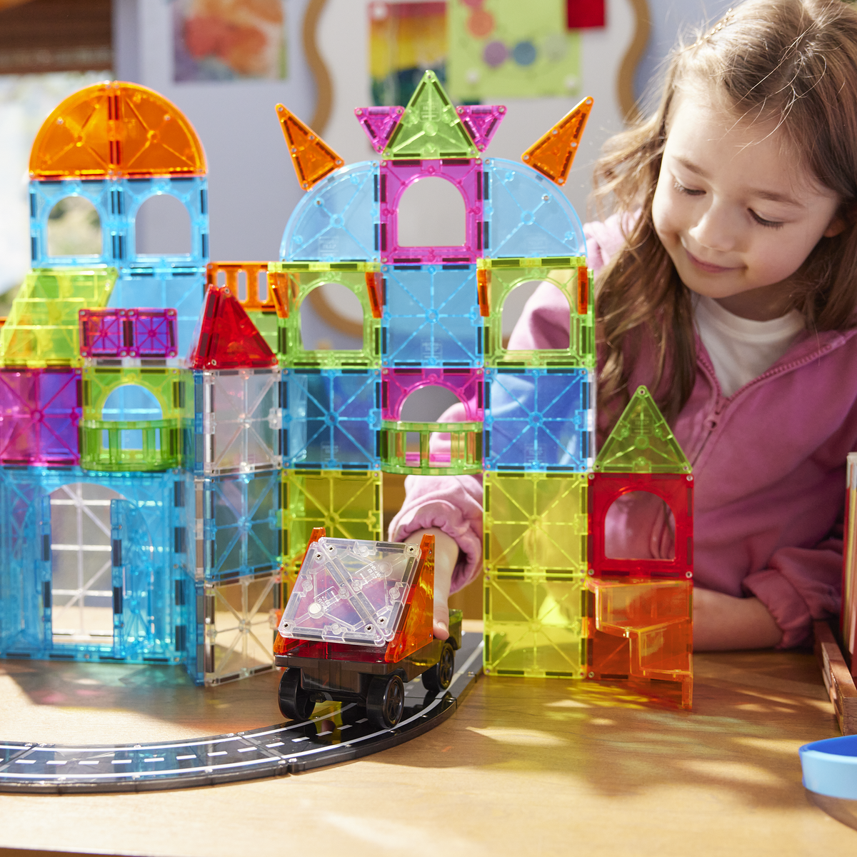 Children playing with colorful magnetic building blocks on a table.