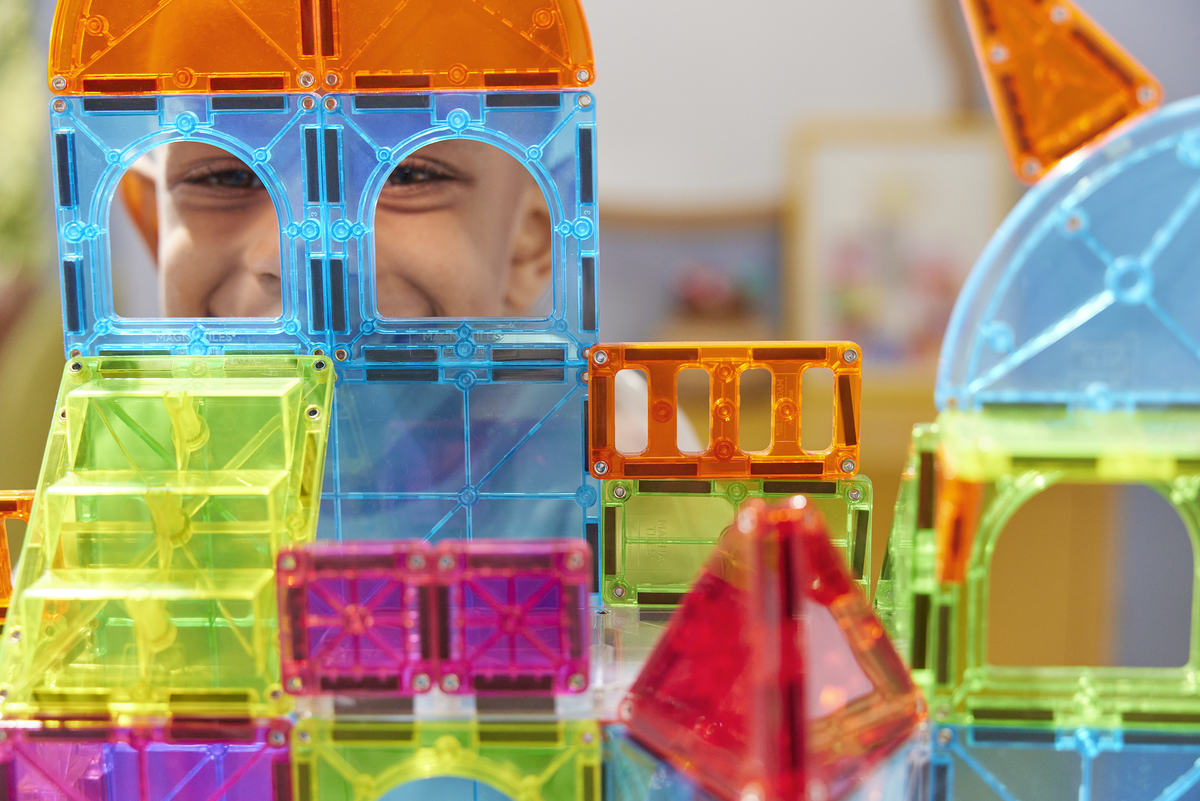 Child playing with colorful magnetic building blocks indoors