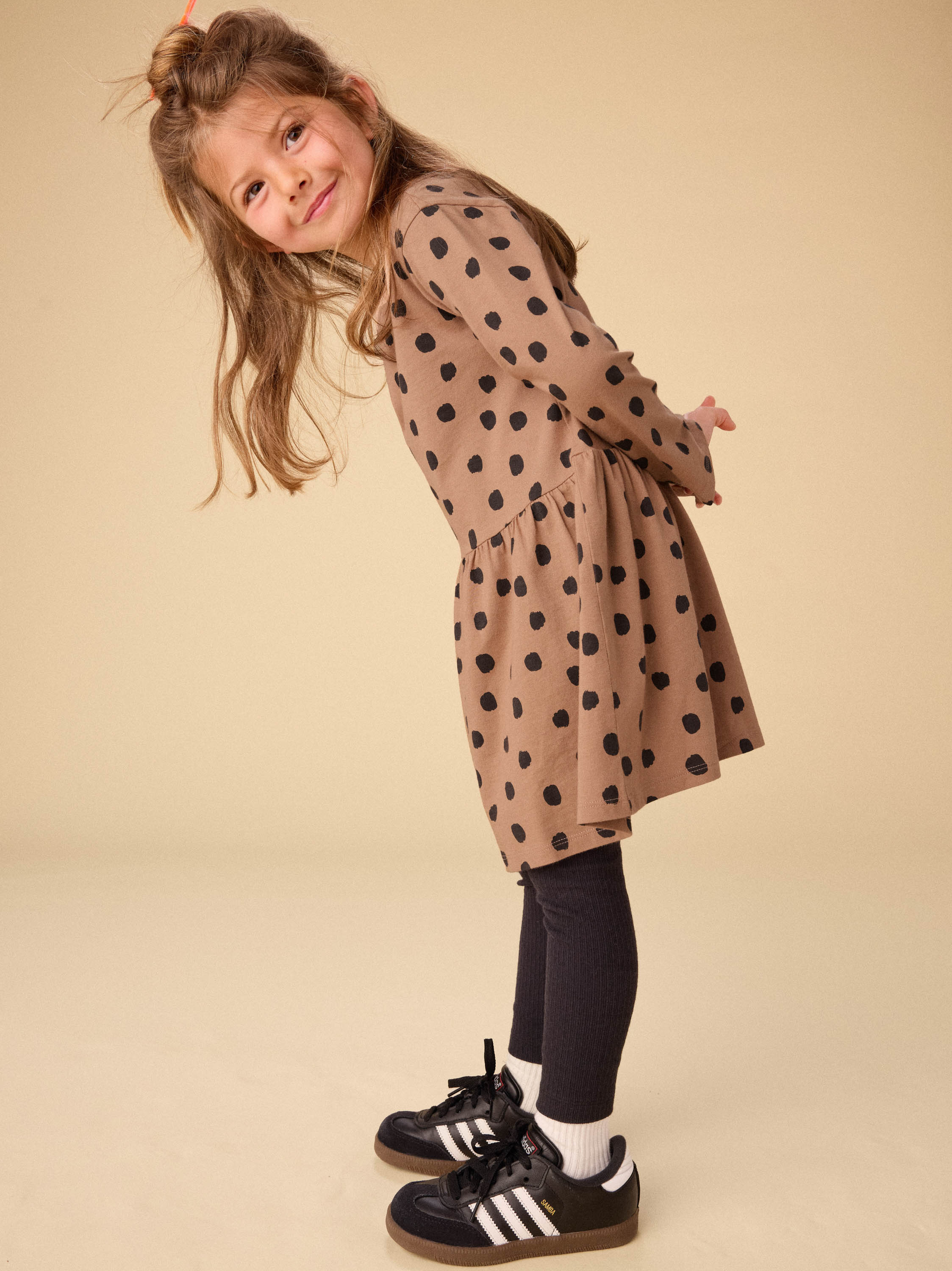 Child wearing a polka dot coat on a beige background