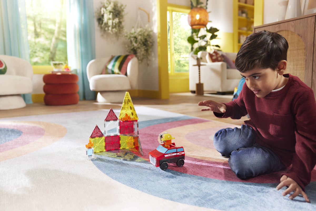 Child playing with colorful building blocks on a rug in a living room.