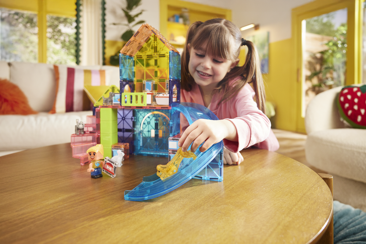 Child playing with colorful toy blocks on a wooden table in a bright room.