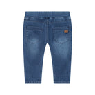 Back view of a pair of blue denim cropped pants for kids, featuring a ribbed waistband, two back pockets, and a small brown brand patch on the right pocket, shown against a plain white background.