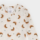 A close-up of a long-sleeve crewneck top by Firstst, featuring an all-over print of brown croissants and small green pine sprigs on a light cream background.
