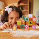 Child playing with colorful magnetic building blocks on a wooden table.