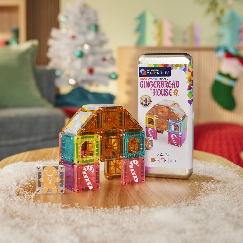 Colorful magnetic building blocks and a gingerbread house-themed packaging on a table with a festive background.