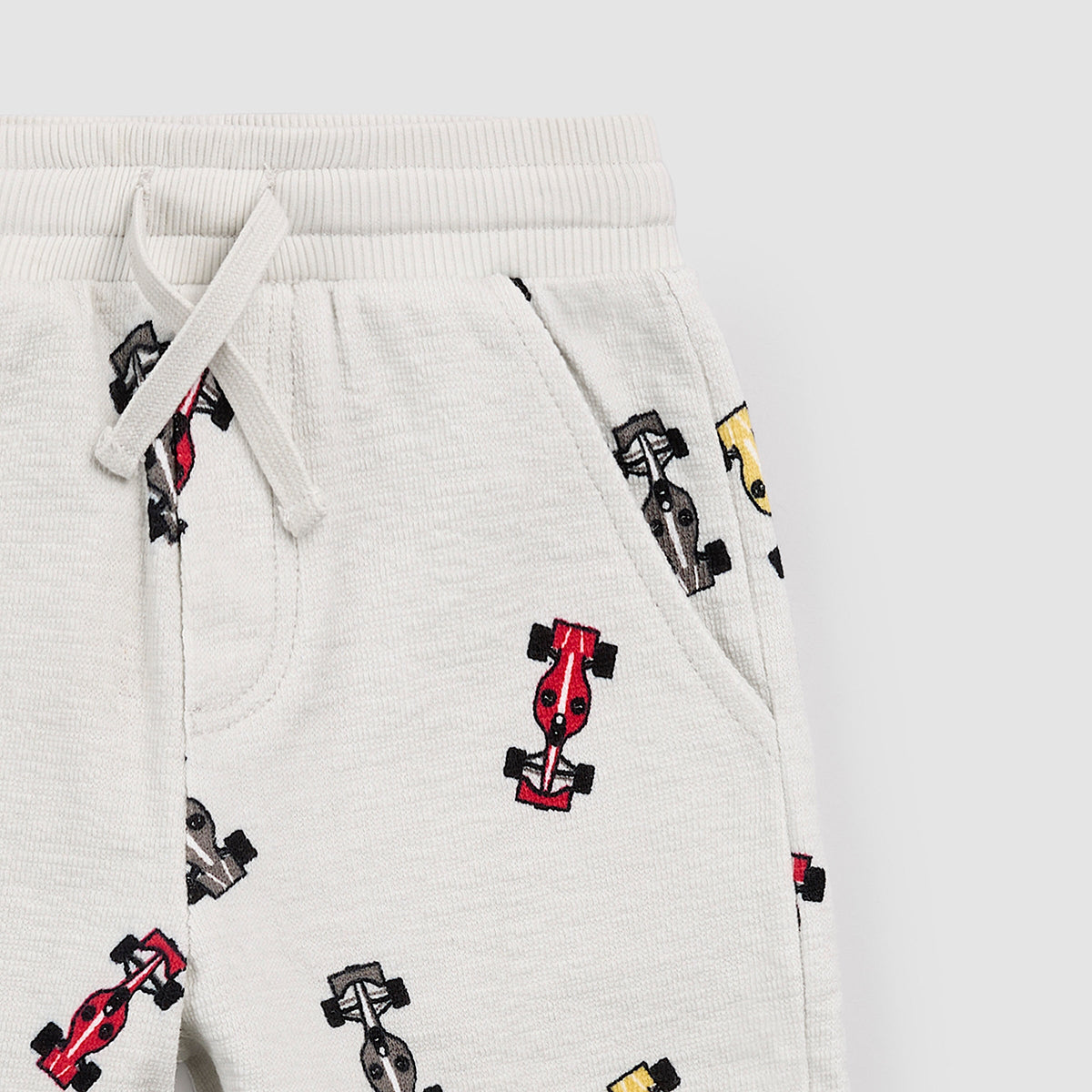 Light gray sweatpants with Formula 1 car pattern on a light gray background