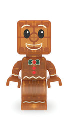 A gingerbread-themed toy minifigure with a square head, brown body, white icing details, and a green and red bow tie, centered on a plain white background.