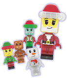 A set of five Christmas-themed toy minifigures, including a large Santa Claus figure and four smaller festive figures in green, brown, and white, isolated on a white background with a faint purple glow effect.