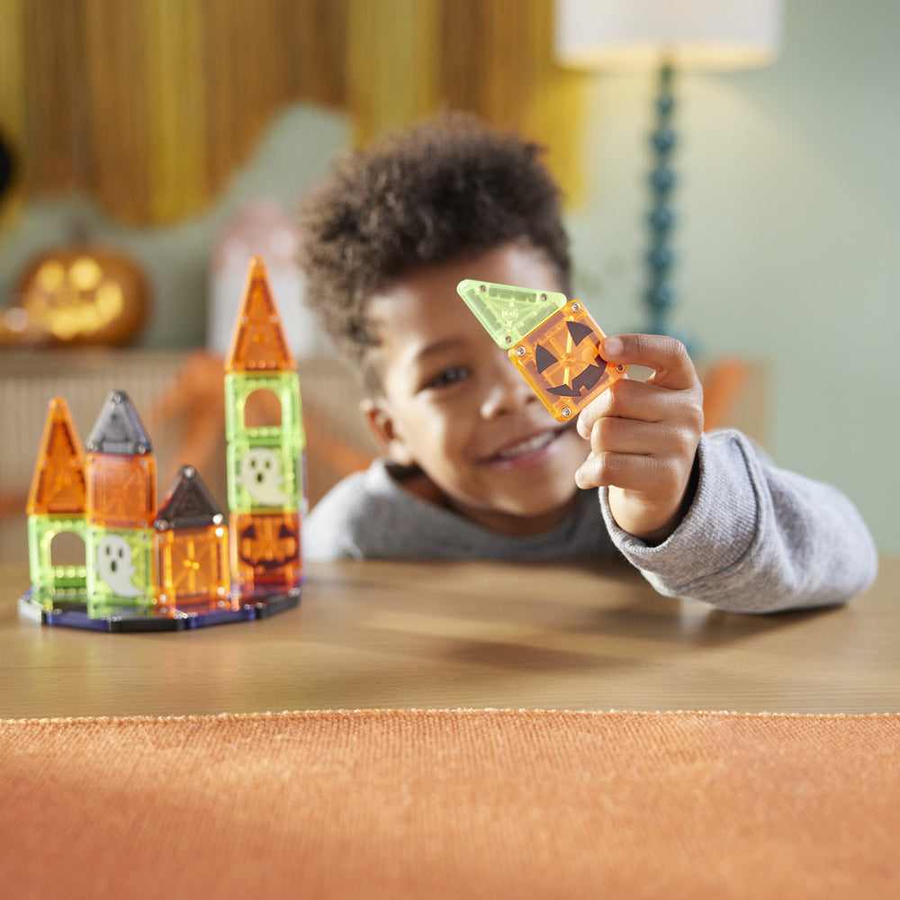 Child playing with Halloween-themed building blocks on a table.