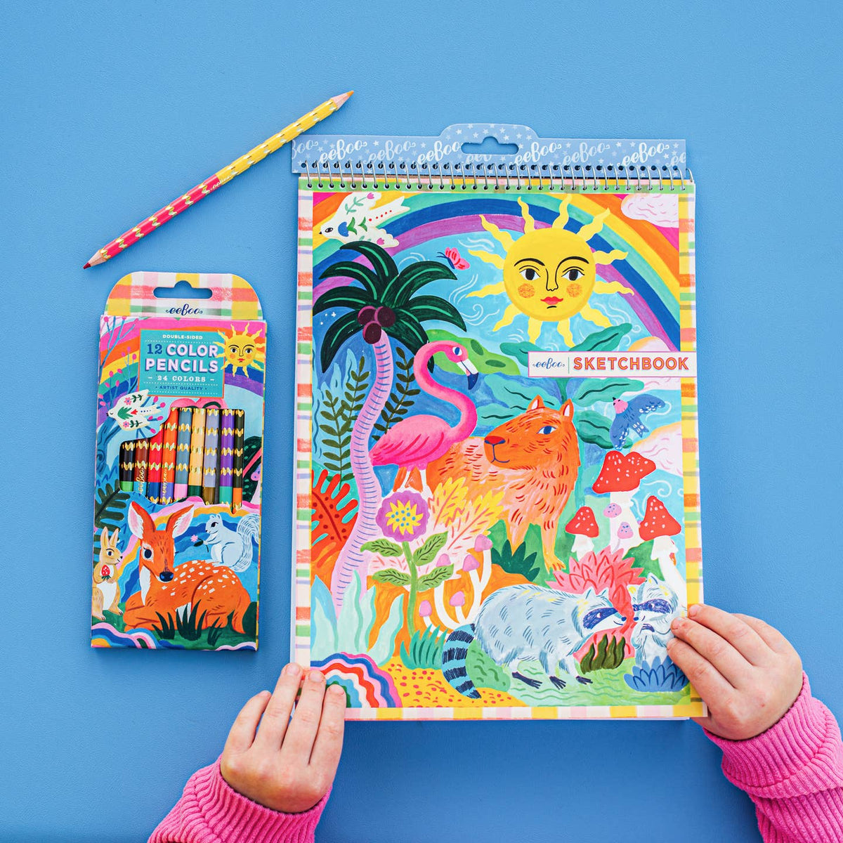 Colorful sketchbook and coloring pencils on a blue background