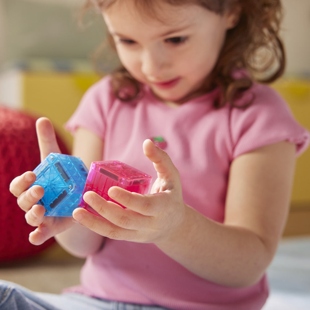 Child holding two colorful transparent blocks in their hands